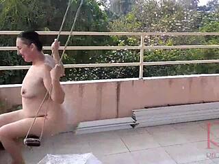 Een huisvrouw geniet van swingen zonder ondergoed terwijl ze onder een paraplu schuilt in een klassieke video over de hele lengte